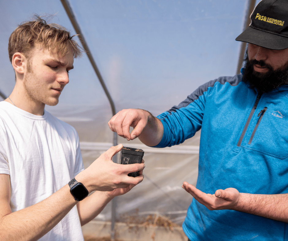 Student members of Bog Turtle Creek Farm plant a seed in the greenhouse.